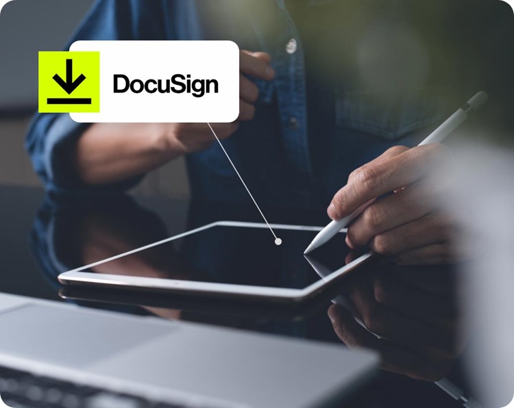 Person signing a digital document on a tablet with a stylus, with a DocuSign icon displayed.