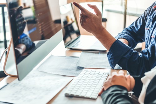 Two people working at a computer while reviewing digital information, representing how organizations evaluate and select the right eProcurement platform.