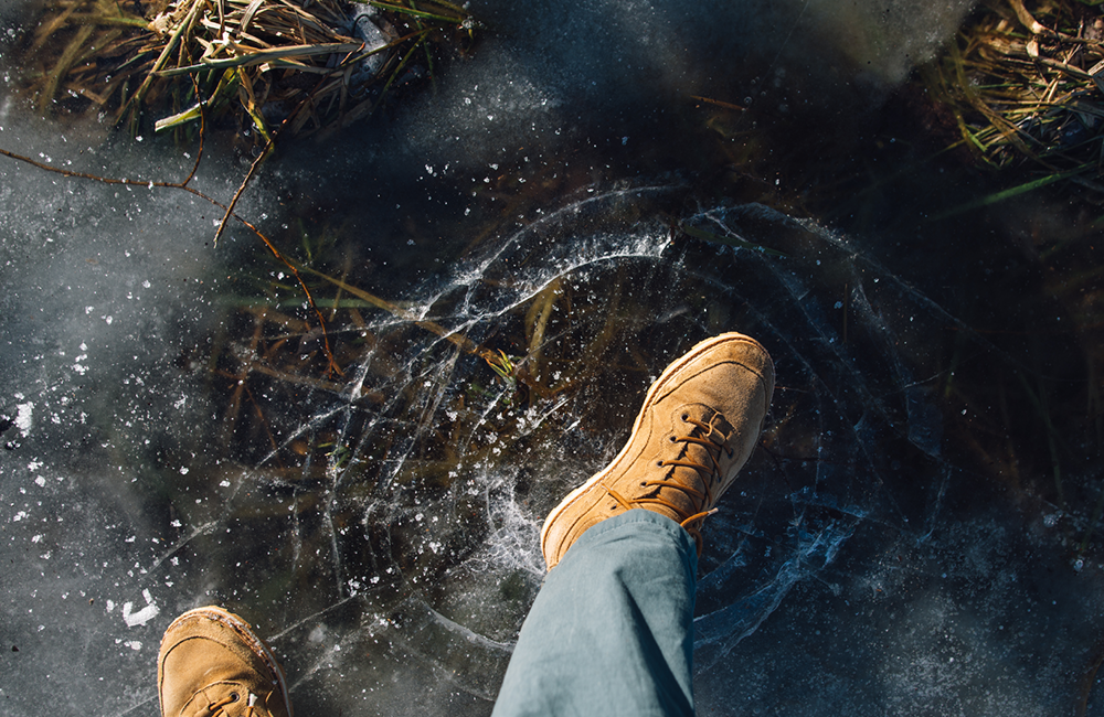 Close-up of a person standing on thin, cracked ice, symbolizing risks and pitfalls in procurement evaluation.