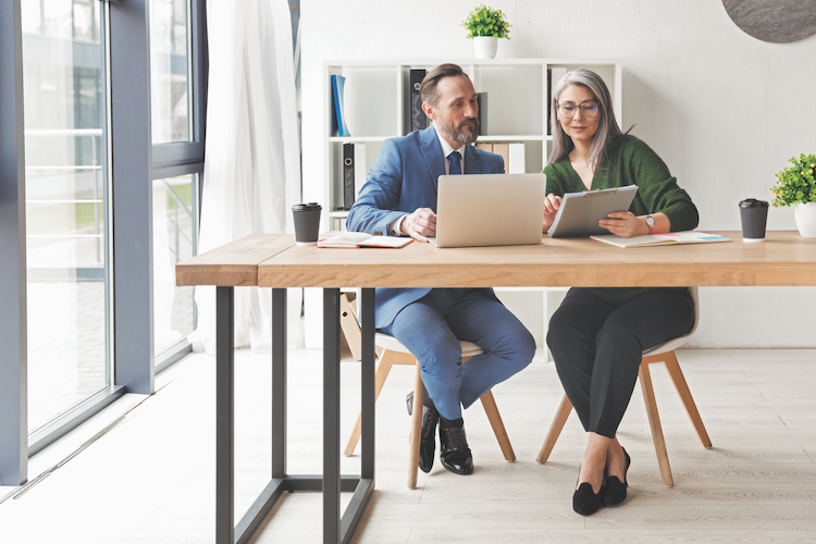 Two professionals reviewing information on a laptop and tablet, representing how digital procurement platforms help reduce organizational risk.