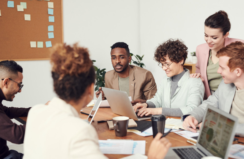 Diverse team collaborating around a table with laptops and documents, symbolizing how local sourcing and eProcurement support flexibility, diversity, and sustainable community growth.