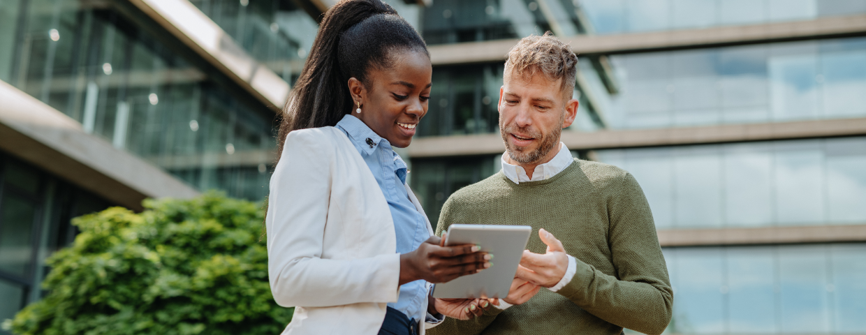 Two business professionals reviewing information on a tablet, symbolizing the steps to becoming MBE or WBE certified in Canada to access government contracts.
