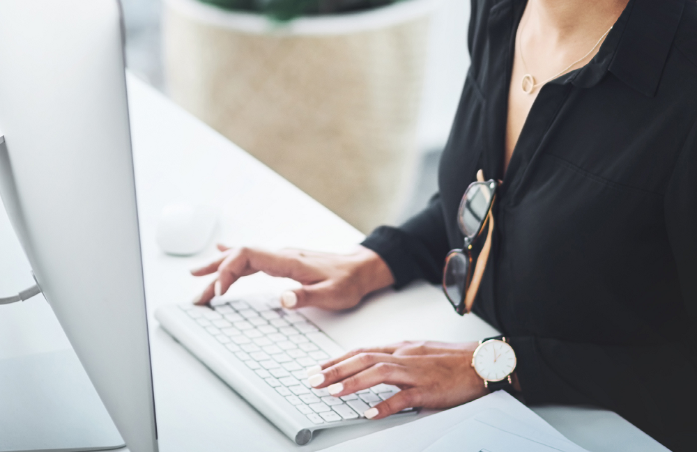 Close-up of a professional typing on a desktop computer, representing learning the myths and facts about switching to eProcurement.