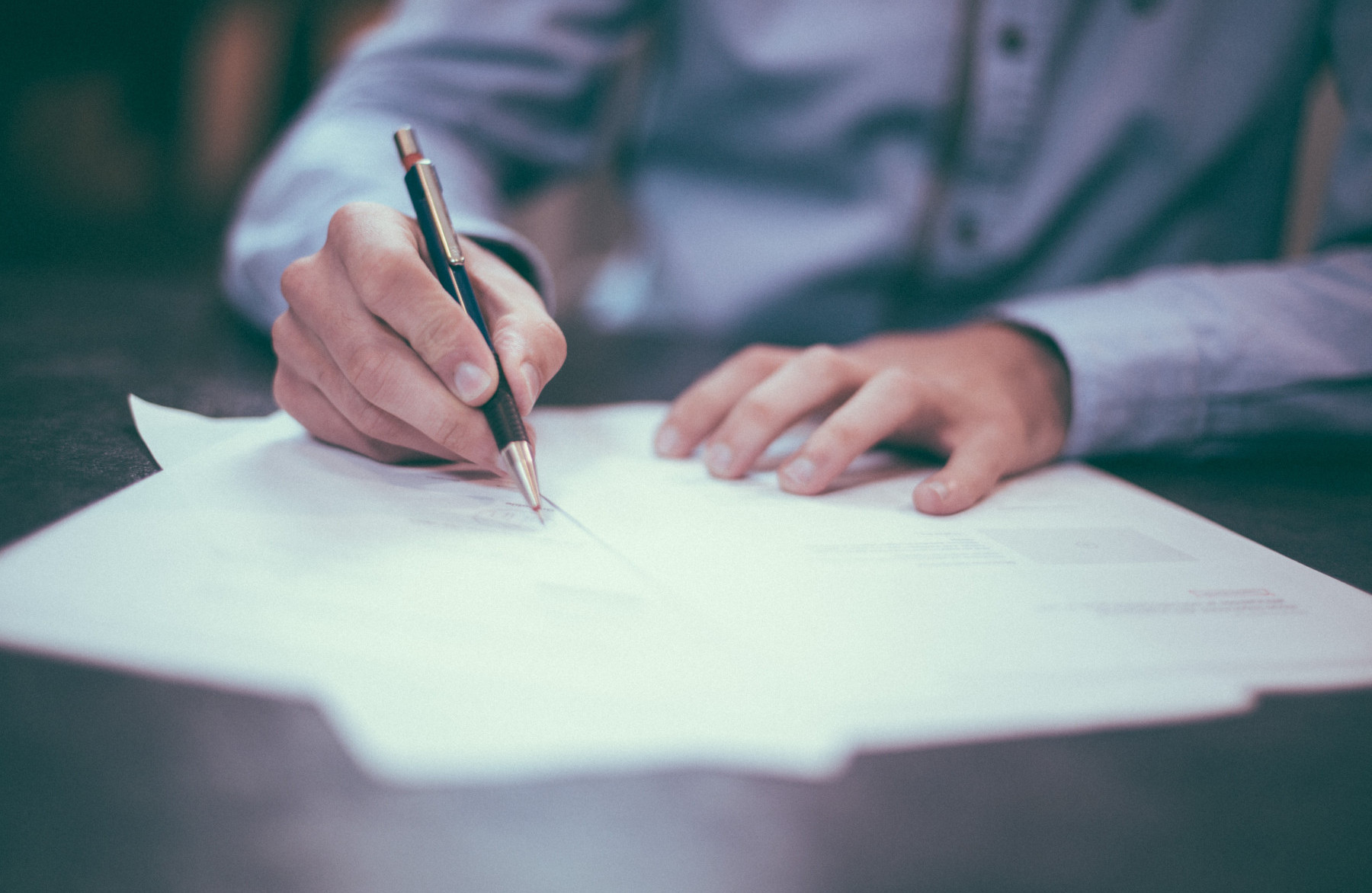 Close-up of a person signing documents, representing updated Surety Association of Canada bond forms and industry guidance.