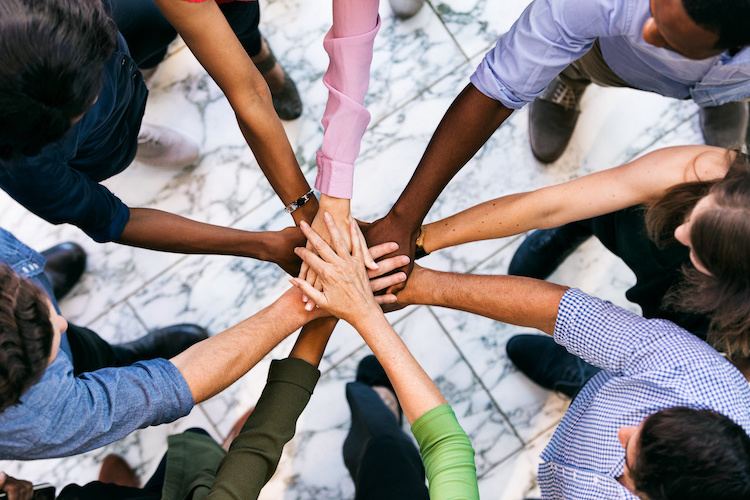 Group of diverse people joining hands in a circle, symbolizing supplier diversity and inclusive procurement strategies.