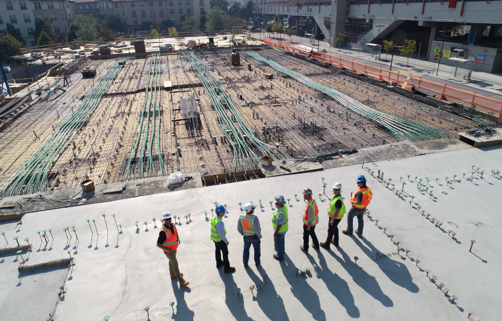 Construction workers in safety gear inspecting a large building site, representing how surety bonds help protect against construction risks.