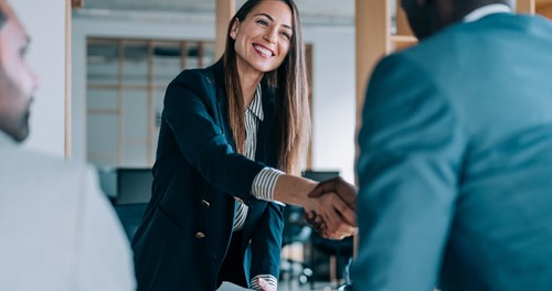 Smiling businesswoman shaking hands with a colleague during a meeting.
